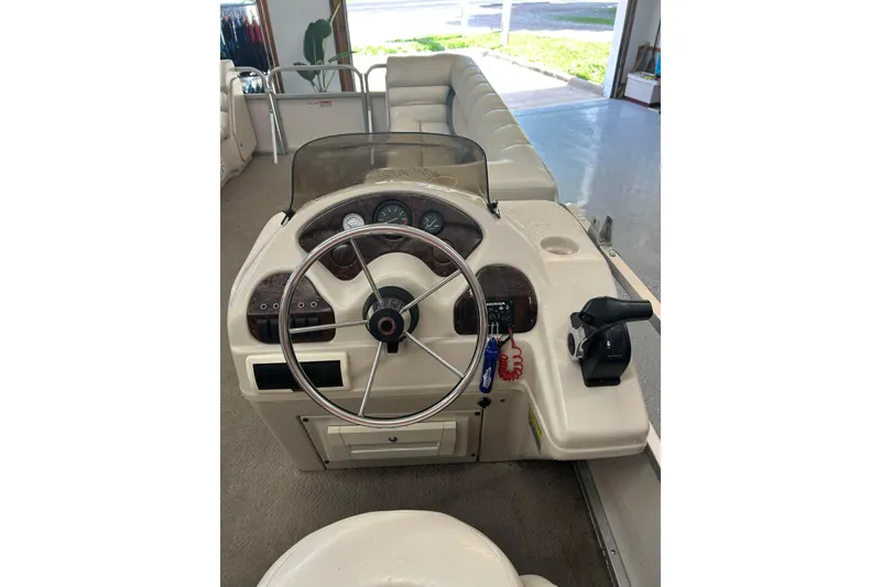 Slide: The Image of 2005 Manitou 22 Oasis boat dashboard with steering wheel and controls in a showroom. - 5