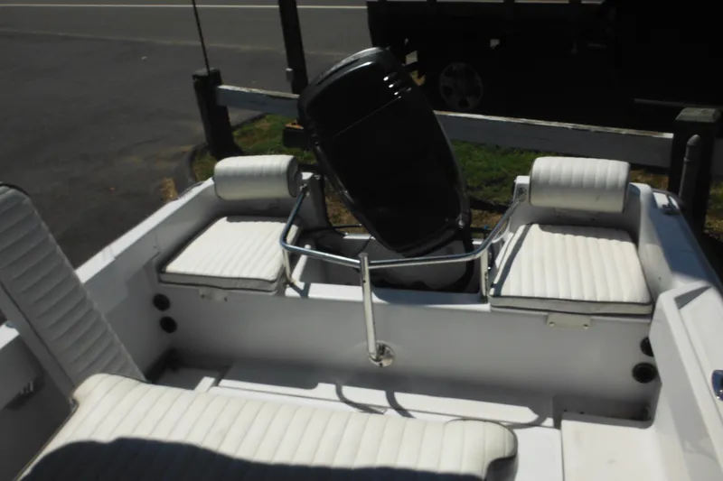 Slide: The Image of 1996 Boston Whaler Outrage 17 boat interior with white cushioned seating and motor. - 24