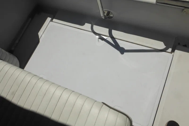 Slide: The Image of 1996 Boston Whaler Outrage 17 interior with white seating and storage compartment. - 26