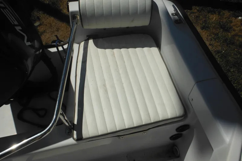 Slide: The Image of 1996 Boston Whaler Outrage 17 boat seat with white upholstery and metal railing. - 28