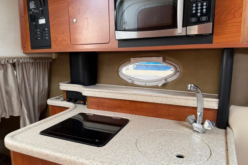 Slide: The Image of 2008 Rinker 260 Express Cruiser kitchen with microwave, stovetop, and sink. - 8