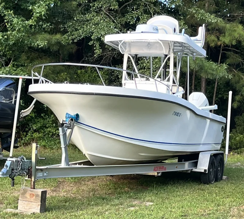 The Image of 1998 Dusky 256 boat on trailer, parked on grass with trees in background. - 0
