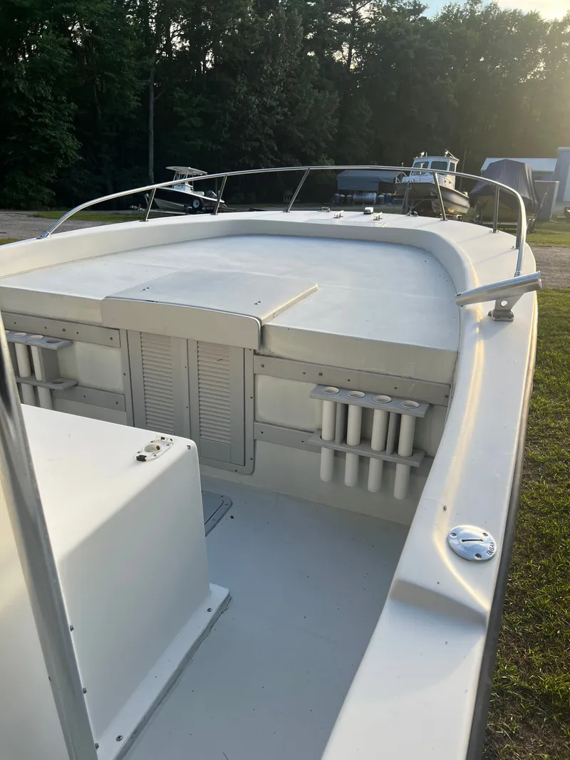 Slide: The Image of 1998 Dusky 256 boat deck with rod holders, surrounded by trees and sunlight. - 11