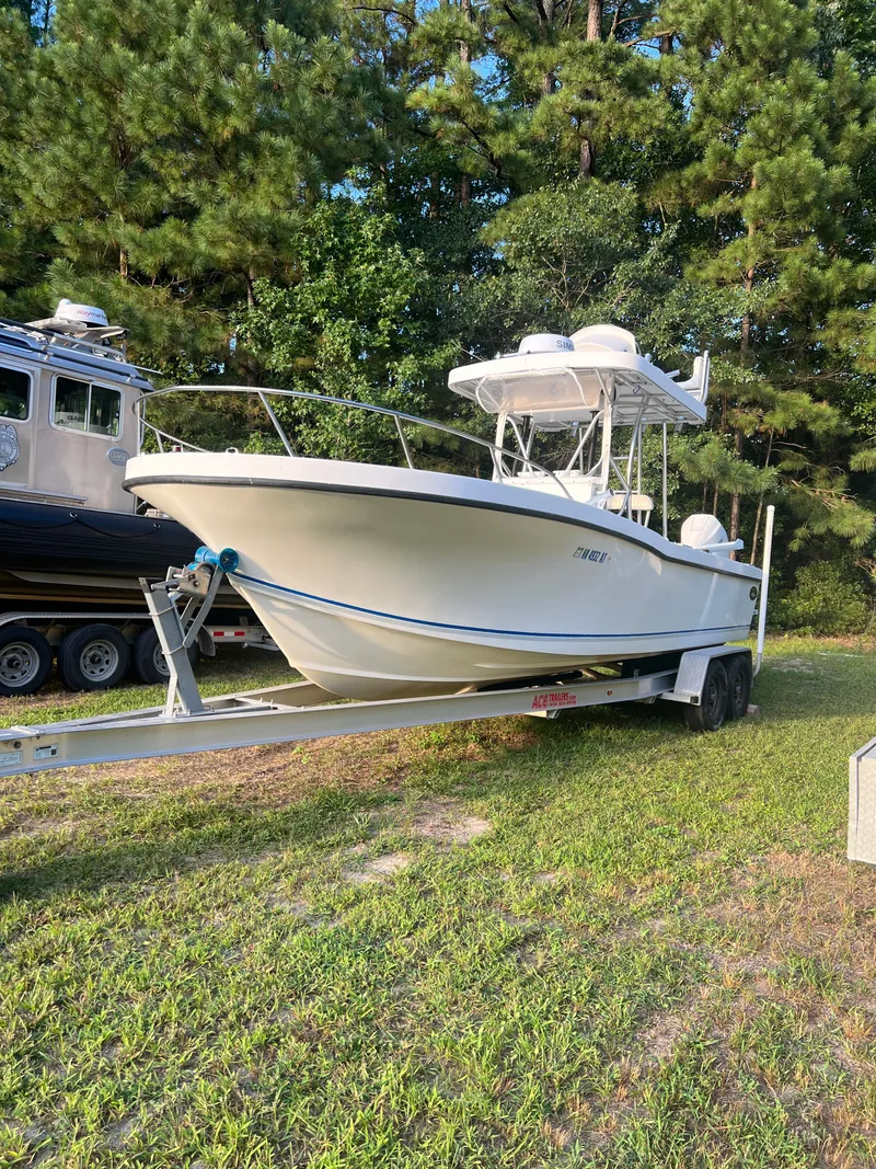 Slide: The Image of 1998 Dusky 256 boat on trailer, parked on grass with trees in background. - 3