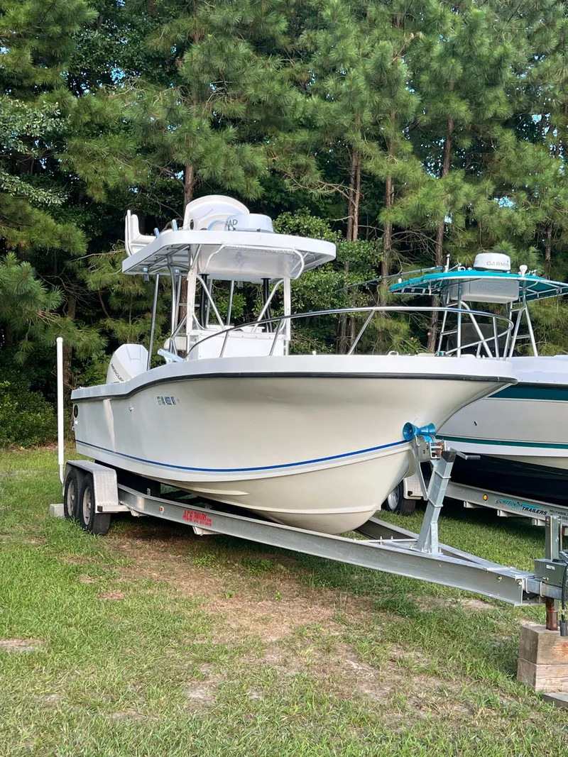 Slide: The Image of 1998 Dusky 256 boat on trailer, parked on grass with trees in background. - 5