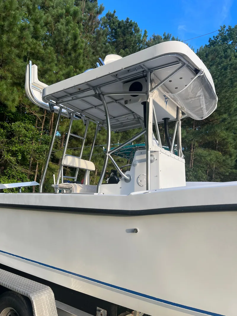 Slide: The Image of 1998 Dusky 256 boat with T-top, parked on trailer, surrounded by trees. - 6