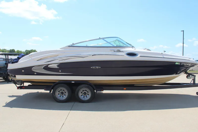 The Image of 2006 Sea Ray 270 Sundeck boat on trailer, parked outdoors under clear sky. - 0