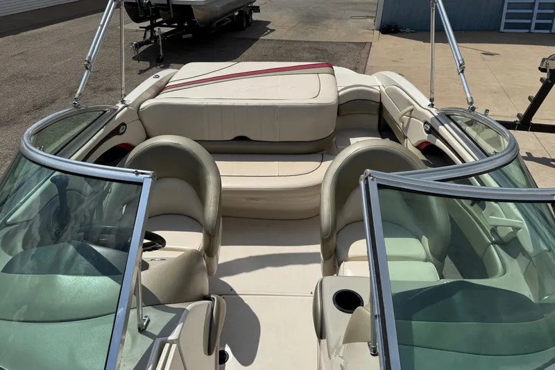 Slide: The Image of 2004 Sea Ray 200 Select boat interior with beige seating and windshield, parked on pavement. - 12
