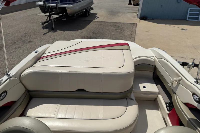 Slide: The Image of 2004 Sea Ray 200 Select boat interior with beige and red upholstery, docked on pavement. - 13