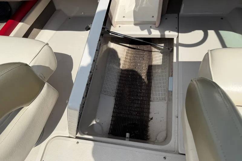 Slide: The Image of 2004 Sea Ray 200 Select boat interior with open storage compartment and beige seating. - 21