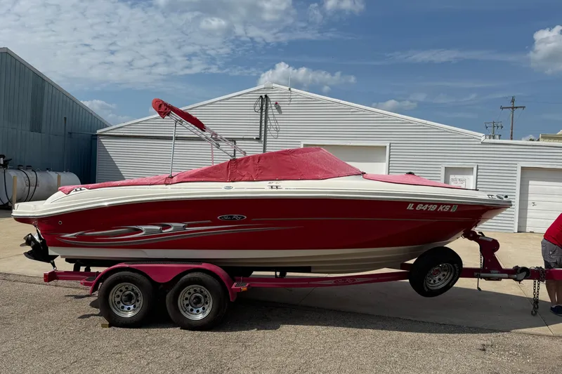 Slide: The Image of 2004 Sea Ray 200 Select boat with red cover on trailer, parked near a building. - 30