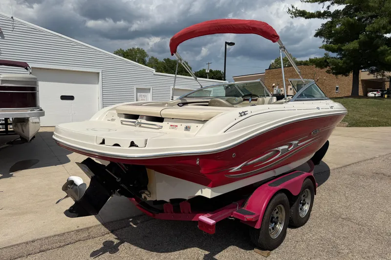 Slide: The Image of 2004 Sea Ray 200 Select boat with red hull on trailer, parked outdoors. - 5