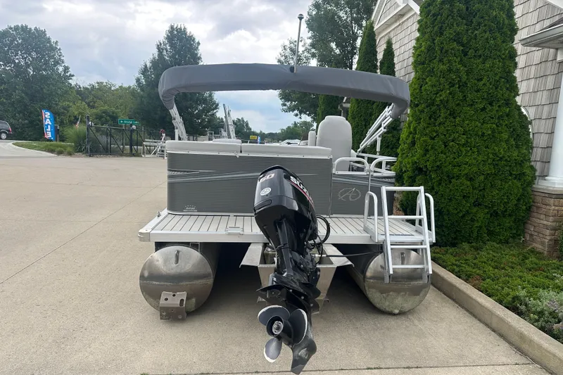 Slide: The Image of 2018 Avalon GS2185 pontoon boat with outboard motor, parked on concrete driveway. - 1