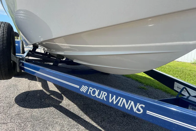 Slide: The Image of 2008 Four Winns H190 boat on a blue trailer, parked on asphalt. - 22
