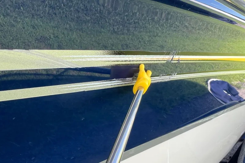 Slide: The Image of 2008 Four Winns H190 boat detailing with yellow tool on blue hull. - 28