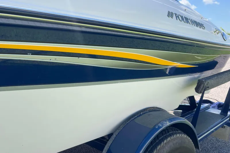 Slide: The Image of 2008 Four Winns H190 boat with blue and yellow detailing on a trailer. - 29