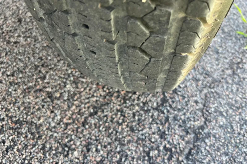 Slide: The Image of Worn tire tread on a 2008 Four Winns H190, showing significant wear on asphalt. - 30