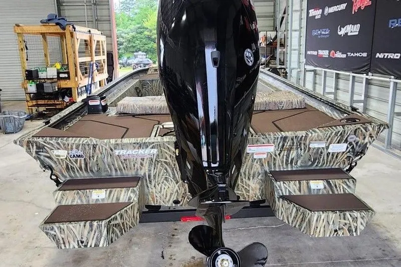 Slide: The Image of 2026 Tracker GRIZZLY® 1860 CC boat with camo design in a garage setting. - 3