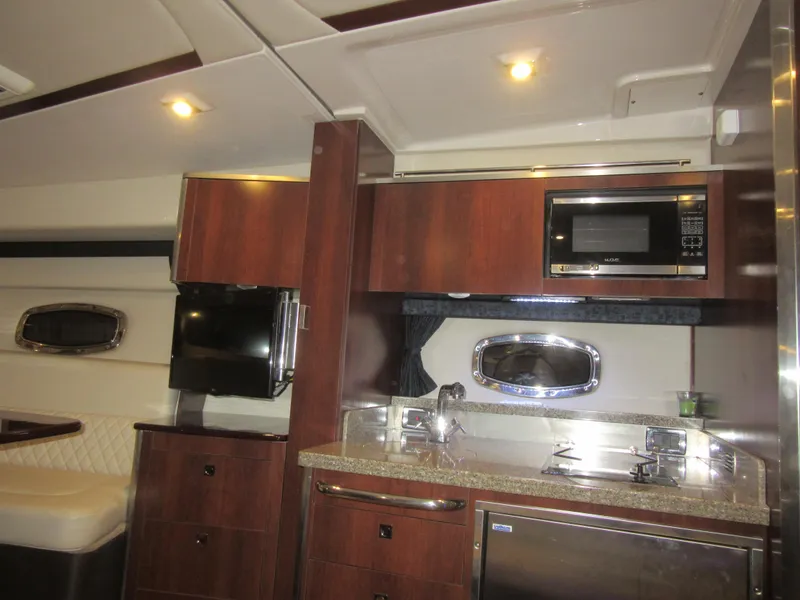 Slide: The Image of 2017 Chaparral 330 Signature yacht interior with kitchenette, wood cabinets, and stainless steel appliances. - 25