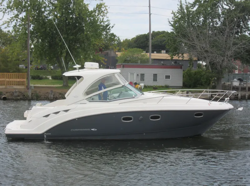 Slide: The Image of 2017 Chaparral 330 Signature boat navigating a calm waterway near a dock. - 3