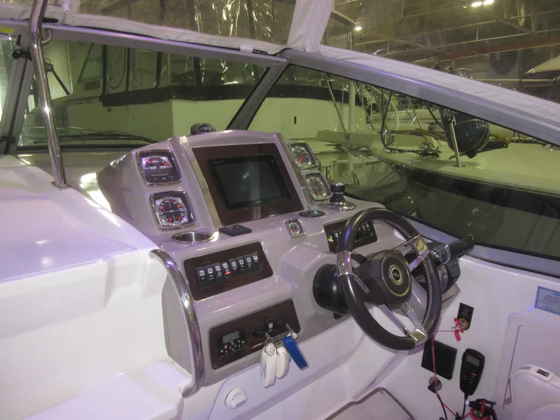 Slide: The Image of 2017 Chaparral 330 Signature boat on a calm waterway, surrounded by trees and buildings. - 4