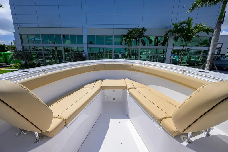 Slide: The Image of 2026 Sportsman Open 302 Center Console boat with beige seating, docked near a modern building. - 7