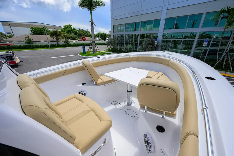 Slide: The Image of 2026 Sportsman Open 302 Center Console boat with beige seating and table, docked near modern building. - 9