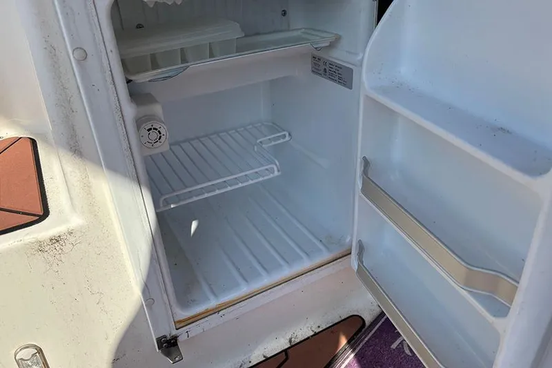 Slide: The Image of Open refrigerator inside 2021 Ranger Tugs R-27 boat, showing empty shelves and door compartments. - 10