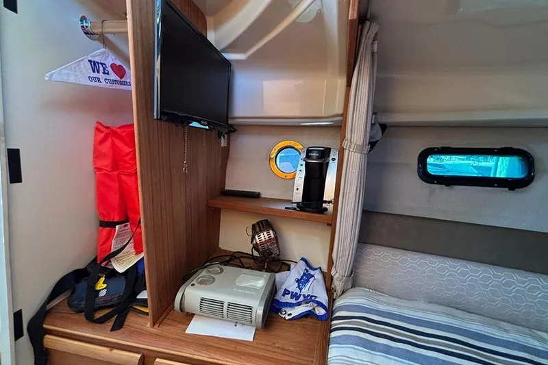 Slide: The Image of 2021 Ranger Tugs R-27 cabin interior with TV, coffee maker, and life jackets. - 13