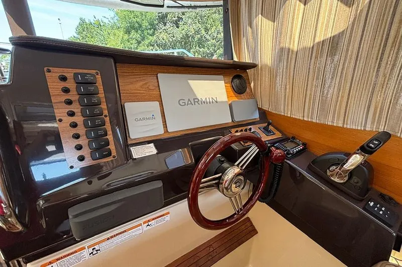 Slide: The Image of 2021 Ranger Tugs R-27 helm with Garmin navigation, wood accents, and steering wheel. - 14