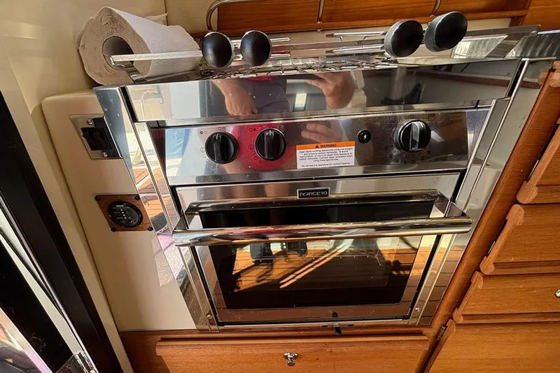 Slide: The Image of 2021 Ranger Tugs R-27 kitchen with stainless steel oven and wooden cabinetry. - 23