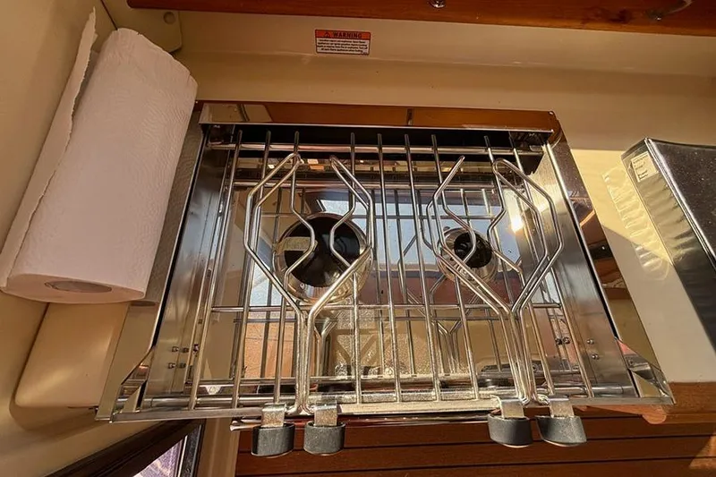 Slide: The Image of 2021 Ranger Tugs R-27 boat kitchen with stainless steel stove and paper towel holder. - 24