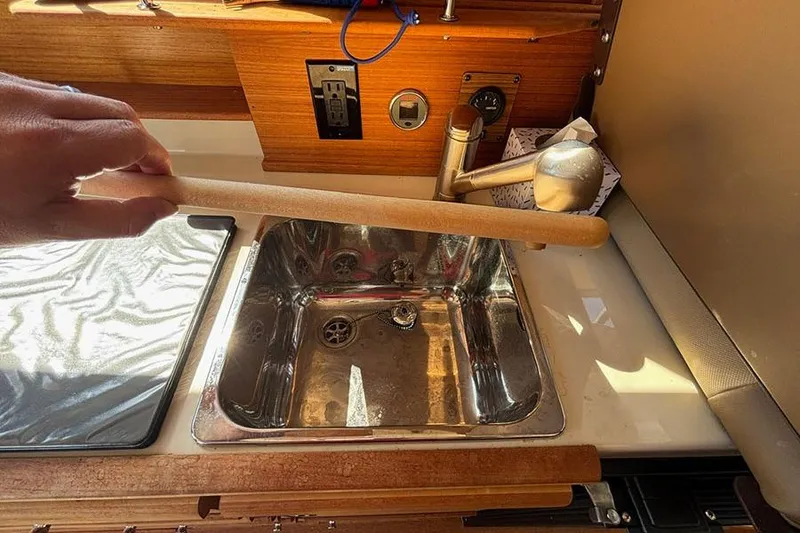 Slide: The Image of 2021 Ranger Tugs R-27 kitchen sink area with wooden countertop and faucet. - 25