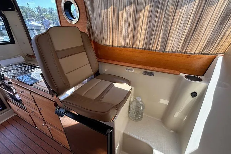Slide: The Image of 2021 Ranger Tugs R-27 interior with seating, kitchenette, and wood accents. - 26