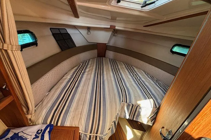 Slide: The Image of 2021 Ranger Tugs R-27 cabin interior with striped bedding and natural light. - 30