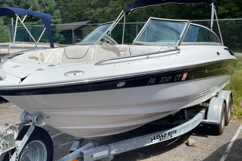 Slide: The Image of 2004 Crownline 216 LS boat on trailer, parked outdoors with trees in background. - 3