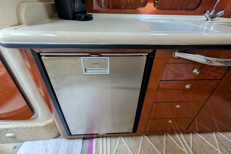 Slide: The Image of 2004 Sea Ray 340 Sundancer interior with Dometic fridge and wooden cabinetry. - 22