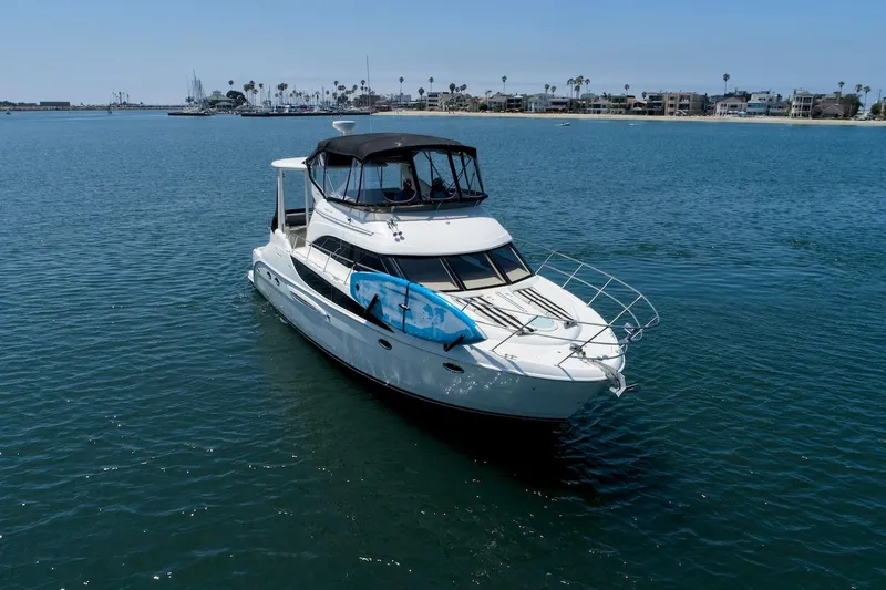 Slide: The Image of 2005 Meridian 459 Aft Cabin Motor Yacht on calm water, with a paddleboard on deck. - 1