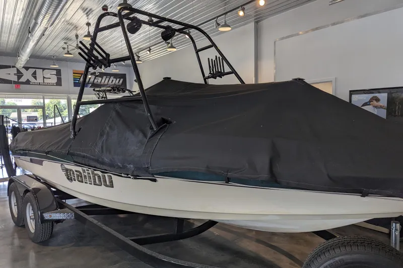 Slide: The Image of 2000 Malibu Sunsetter VLX boat covered, displayed indoors on a trailer. - 23