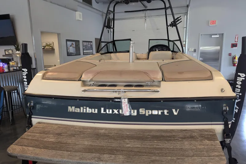 Slide: The Image of 2000 Malibu Sunsetter VLX boat in showroom, rear view with luxury sport branding. - 4