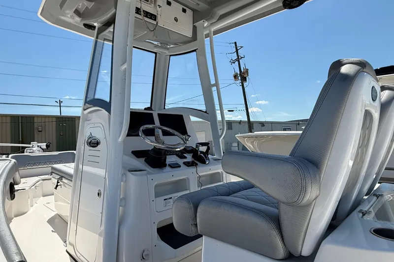 Slide: The Image of 2022 Blue Wave 2800 Makaira boat interior with helm and seating under clear blue sky. - 6