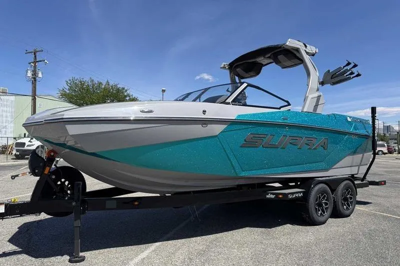 The Image of 2026 Supra SA boat on trailer, teal and gray design, parked outdoors. - 0