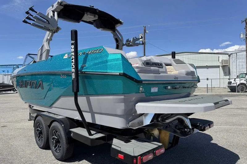 Slide: The Image of 2026 Supra SA boat on trailer, teal and gray design, parked outdoors. - 8