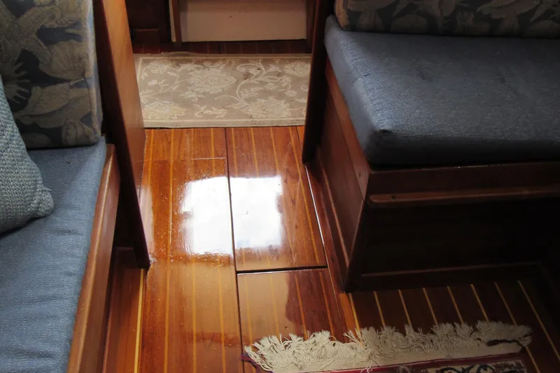 Slide: The Image of Interior of a 1976 Tartan 3800 sailboat with polished wooden flooring and cushioned seating. - 10