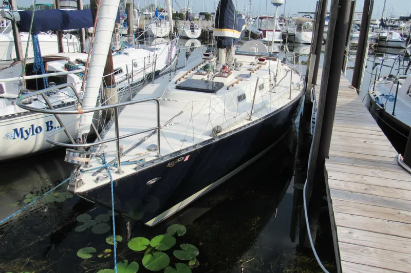 Slide: The Image of 1976 Tartan 3800 sailboat docked in a marina, surrounded by other boats. - 2