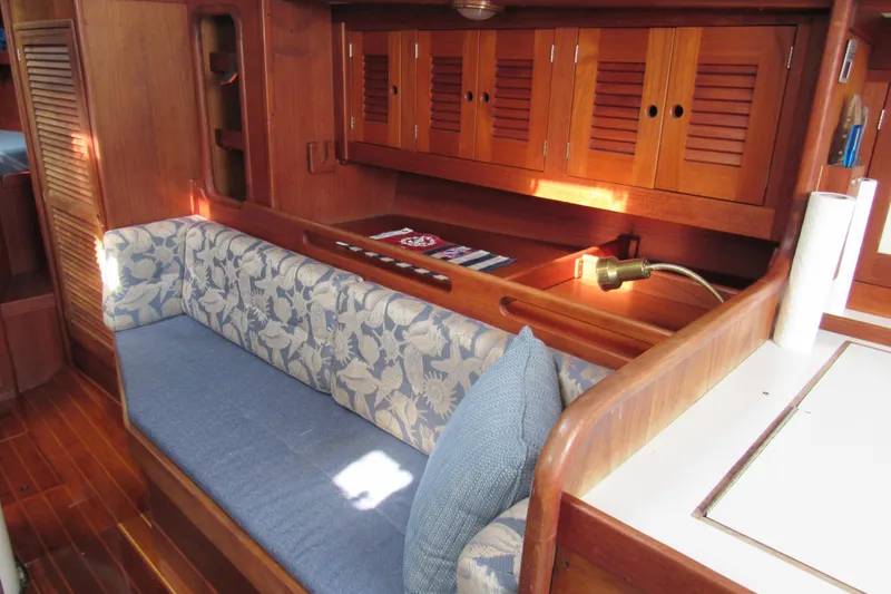 Slide: The Image of Interior of a 1976 Tartan 3800 sailboat with wooden cabinetry and floral-patterned seating. - 4