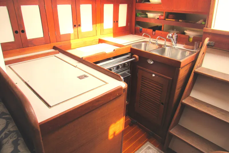 Slide: The Image of 1976 Tartan 3800 yacht kitchen with wooden cabinets, dual sink, and compact stove. - 5
