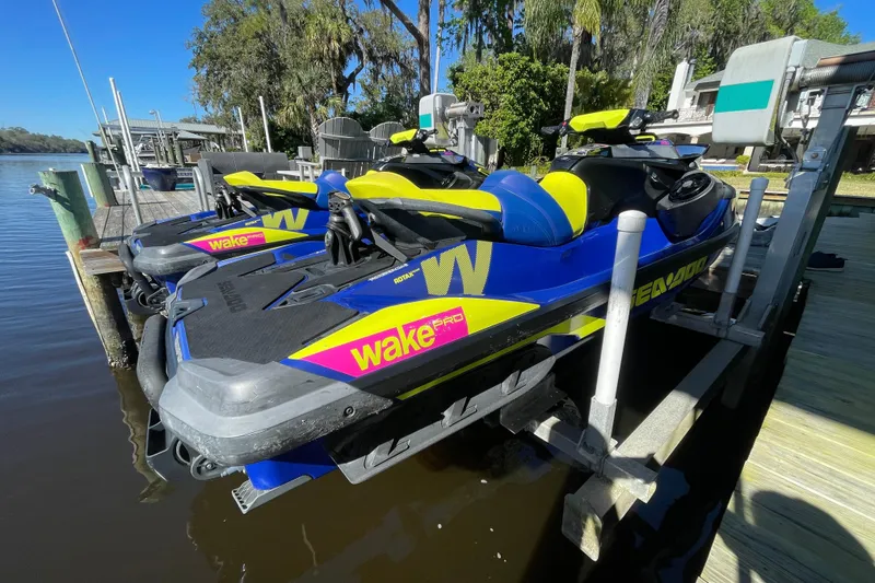 Slide: The Image of 2020 Sea-Doo Wake Pro 230 jet skis docked by a scenic waterfront. - 2