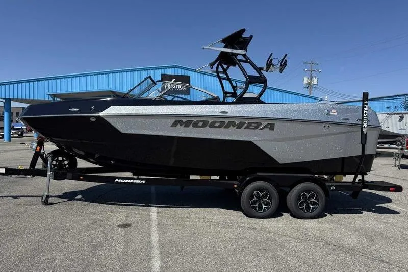 The Image of 2026 Moomba Max boat on trailer in parking lot, blue building background. - 0