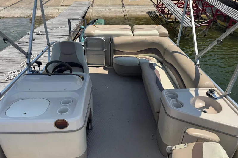 Slide: The Image of 2006 Sun Tracker 240 Party Barge interior with seating and helm, docked by the water. - 3